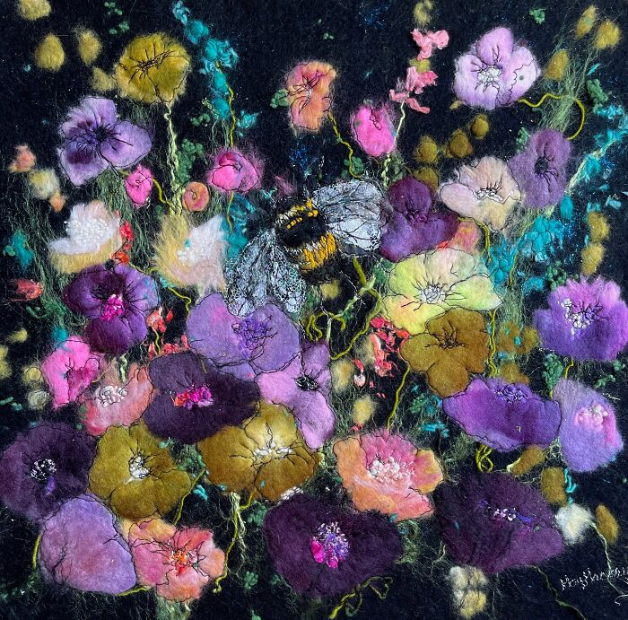 Fiber art of vibrant flowers and a bee by Moy Mackay, showcasing her scenic fiber artworks with intricate details.