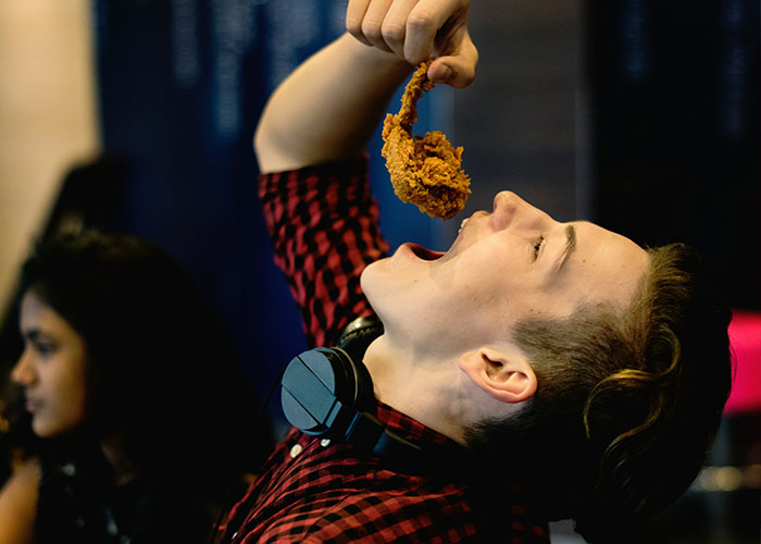 Person in checkered shirt enjoying fried chicken, illustrating unserious reasons for brand boycotts.