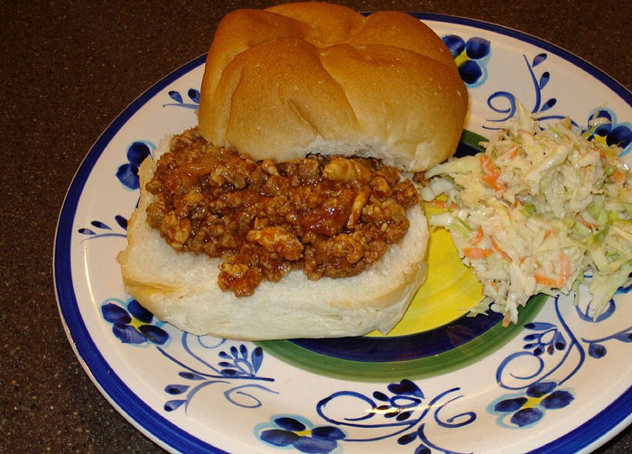 A plate with a classic sandwich and coleslaw, reminiscent of old-school delicacies like Watergate Salad.
