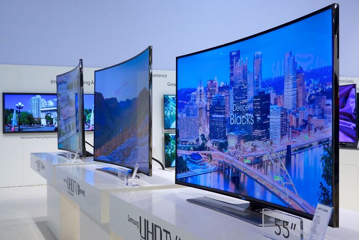 Row of modern curved UHD TVs on display in an electronics store, highlighting gradually disappeared things in technology.