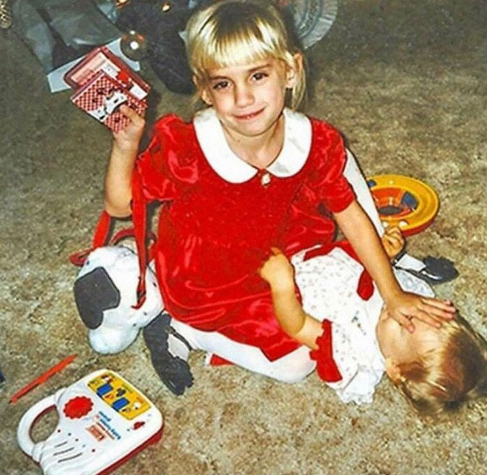 Girl in a red dress posing with toys, showcasing a forgotten moment from history's interesting corners.