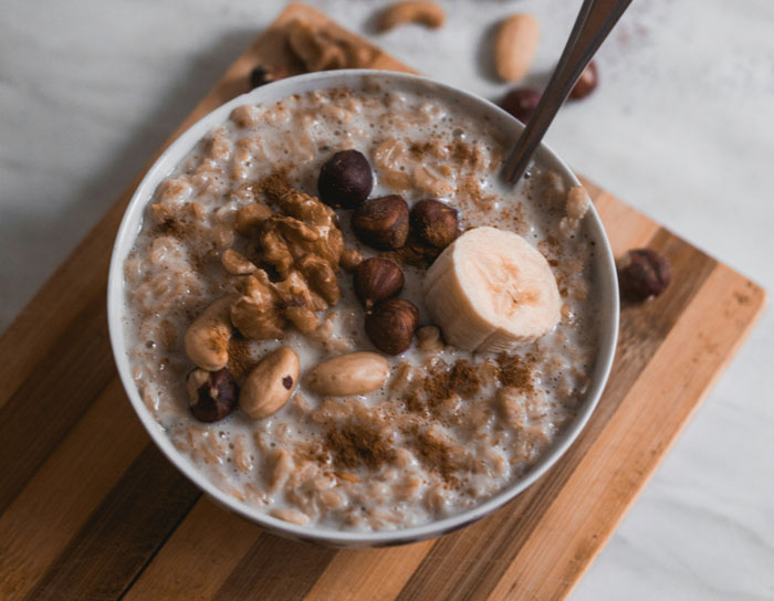 Bowl of oatmeal with nuts and banana, a perfect lazy meal option.