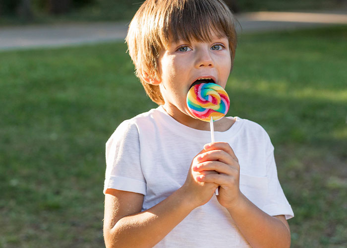 Child enjoying a colorful lollipop outdoors on a sunny day, evoking memorable and amazing dad stories.