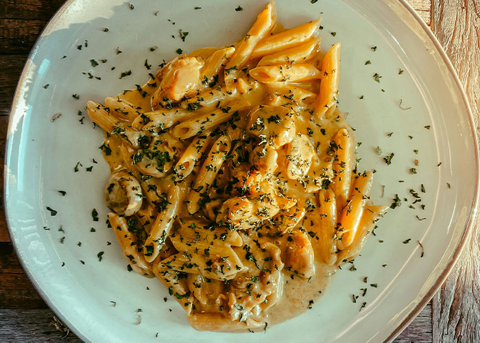 Creamy pasta with herbs on a wide white plate, an example of a dish once considered exotic.