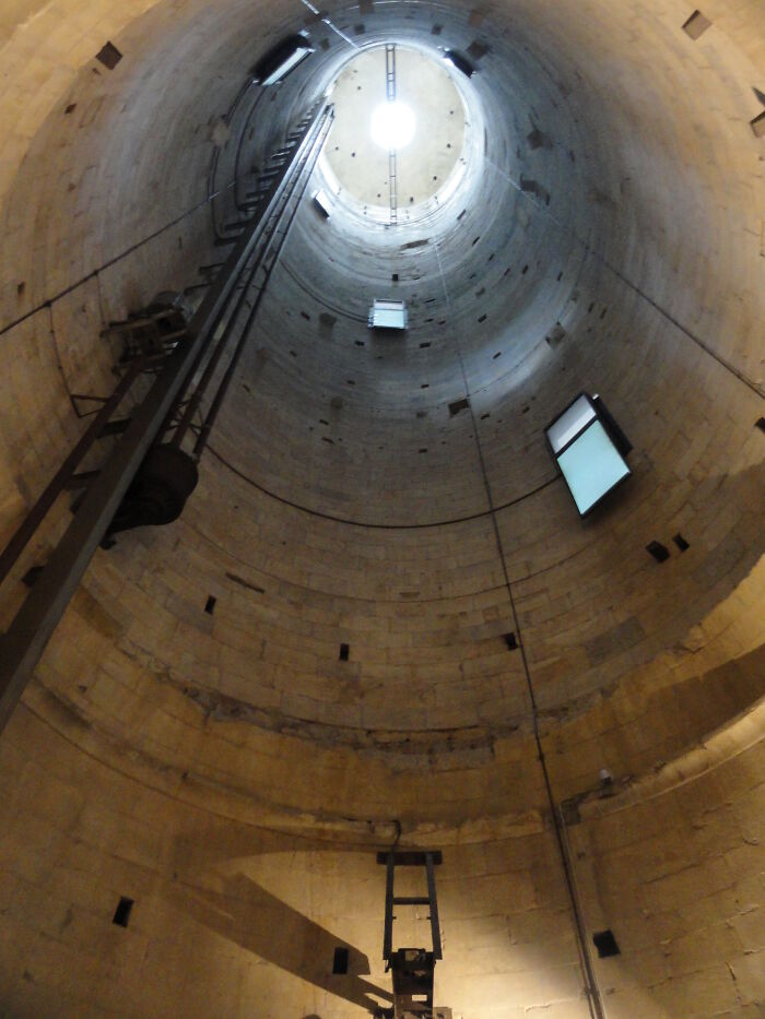 View inside an iconic architectural structure, showing a vertical tunnel with light at the top.