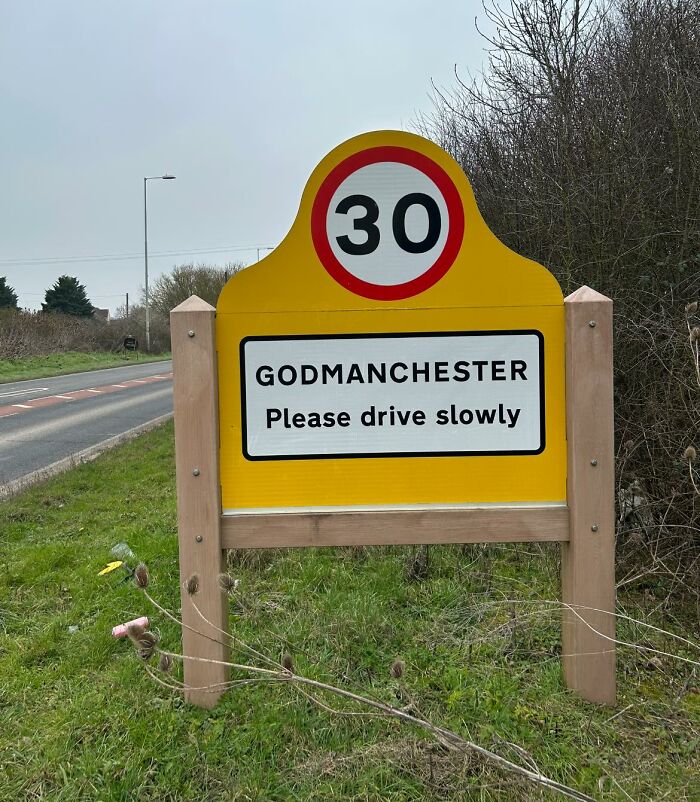 British road sign in Godmanchester with a 30 mph limit, advising drivers to proceed slowly.