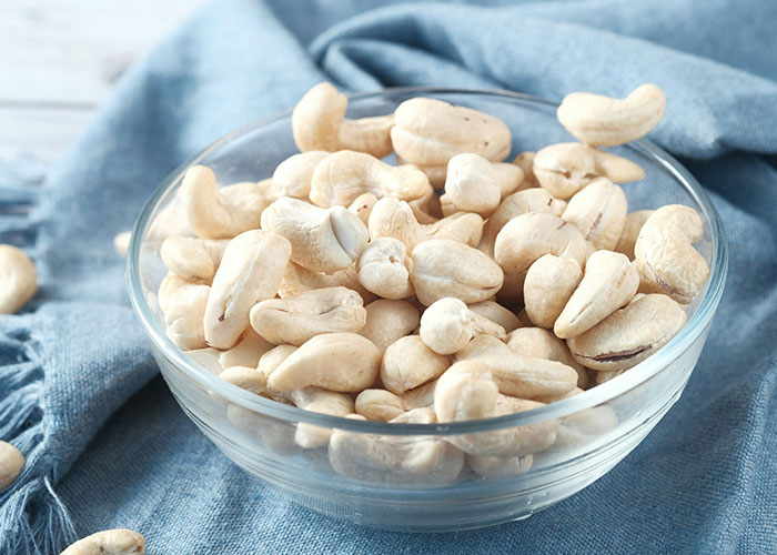 Bowl of cashews on a blue cloth, showcasing foods that were once exotic.