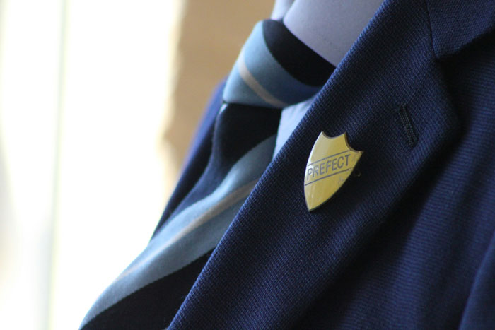 Insignia de prefecto en uniforme escolar azul.