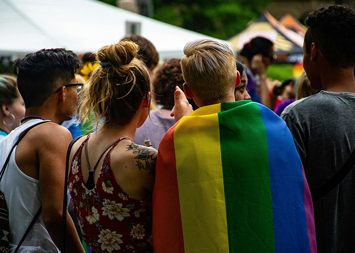 People at a pride event, one wearing a rainbow flag, symbolizing support and positive reactions to coming out.