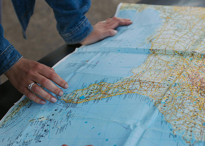 Hands exploring a physical map, highlighting how Gen X experiences life without social media.