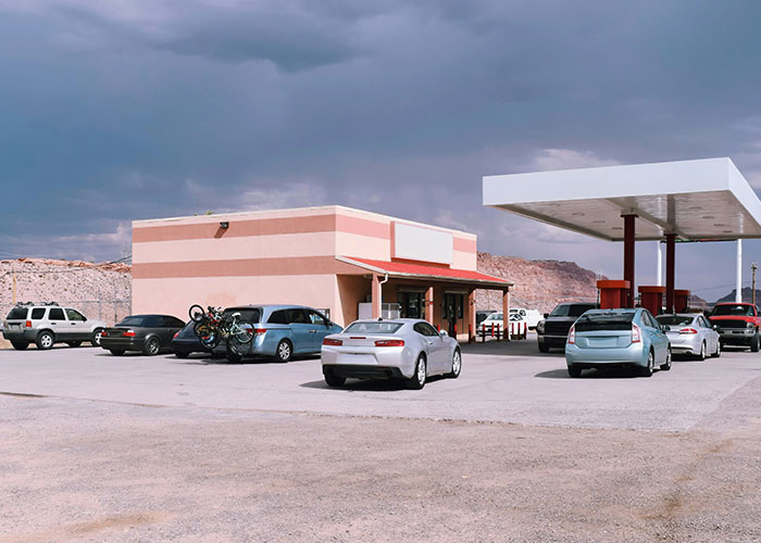 Gas station with parked cars under a cloudy sky, illustrating boycotting brands theme.