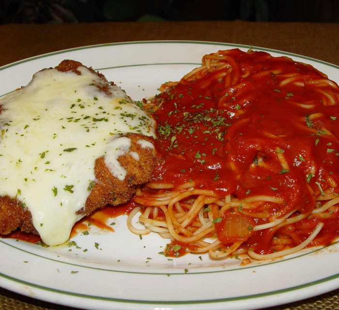 Plate featuring breaded chicken with melted cheese and spaghetti in marinara sauce, a classic old-school delicacy.