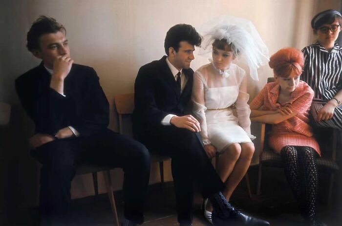 People in vintage attire sitting on chairs, conveying a scene from forgotten corners of history.