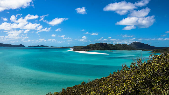Pristine beach with turquoise waters and lush greenery under a clear blue sky.