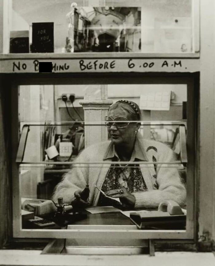 Elderly woman sitting at a ticket booth with vintage decor, representing forgotten corners of history.