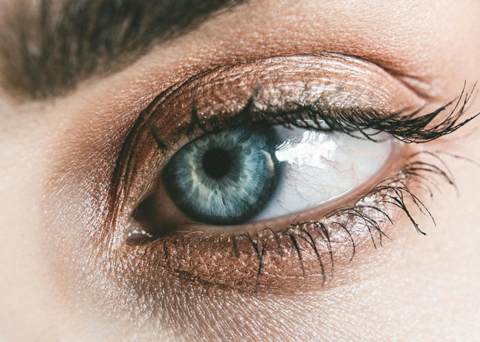 Close-up of a woman's eye with shimmering eyeshadow, showcasing beauty tips for enhancing eye makeup.