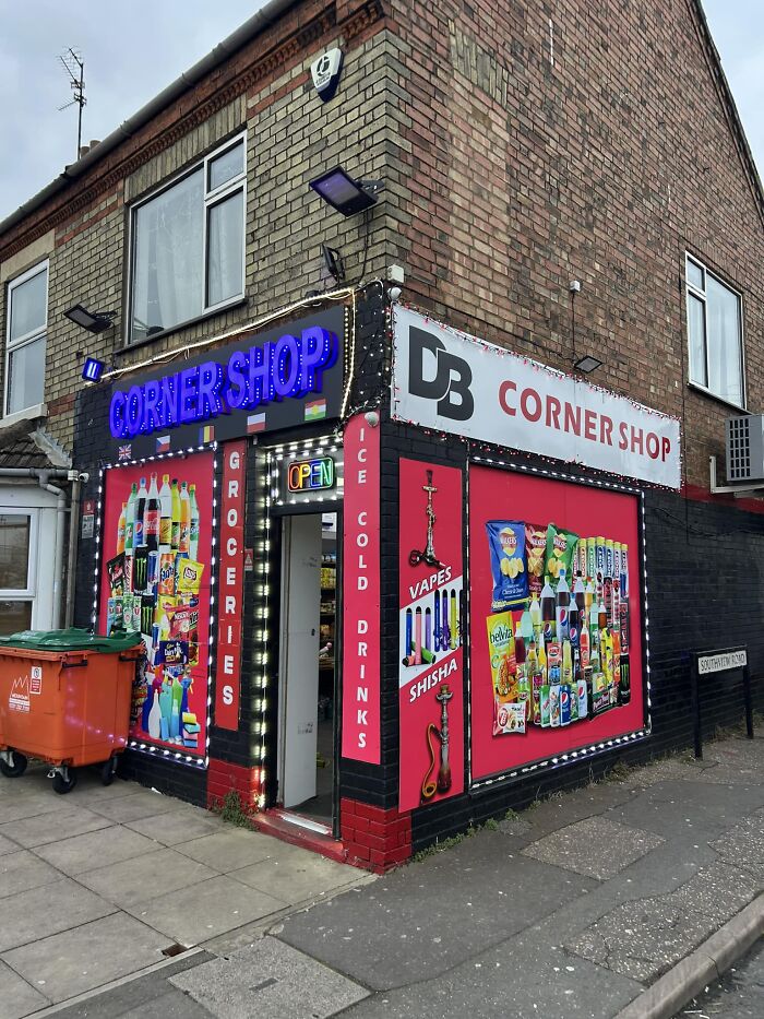 Corner shop in the UK with colorful window displays featuring groceries and drinks, iconic British setting.