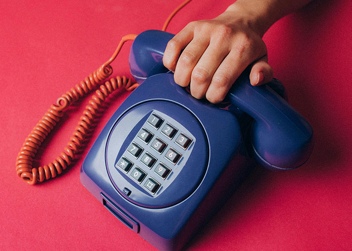 A hand holding a blue rotary phone, symbolizing Gen X nostalgia for life without social media.