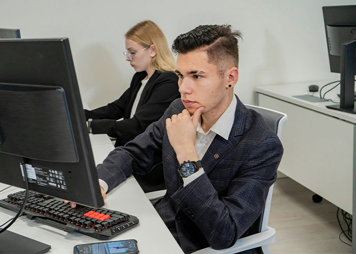 Person in a suit at a computer, appearing thoughtful in an office setting, related to unserious brand boycotting discussion.