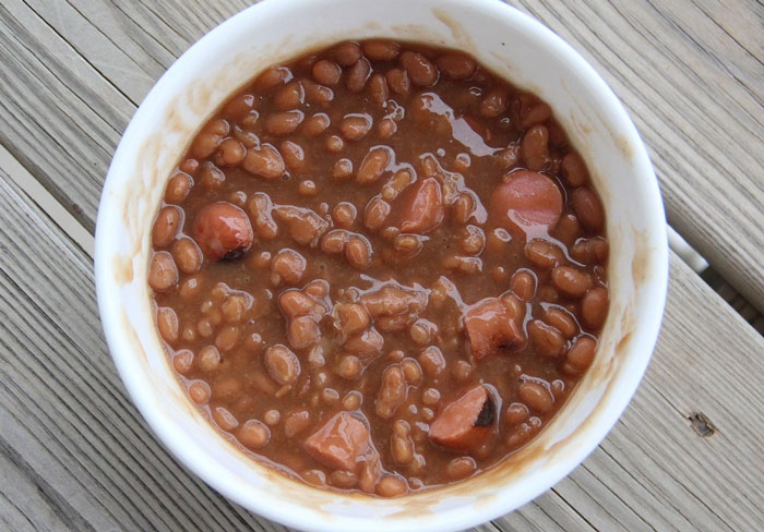 Bowl of old-school delicacy featuring baked beans and sausages, reminiscent of cherished retro recipes.