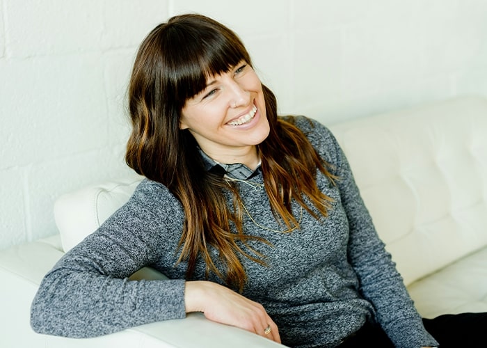 Smiling woman sitting on a white couch, related to parenting mistakes discussion.