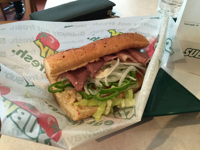 Subway sandwich with deli meat, lettuce, and peppers on a table, highlighting an unexpected firing story context.