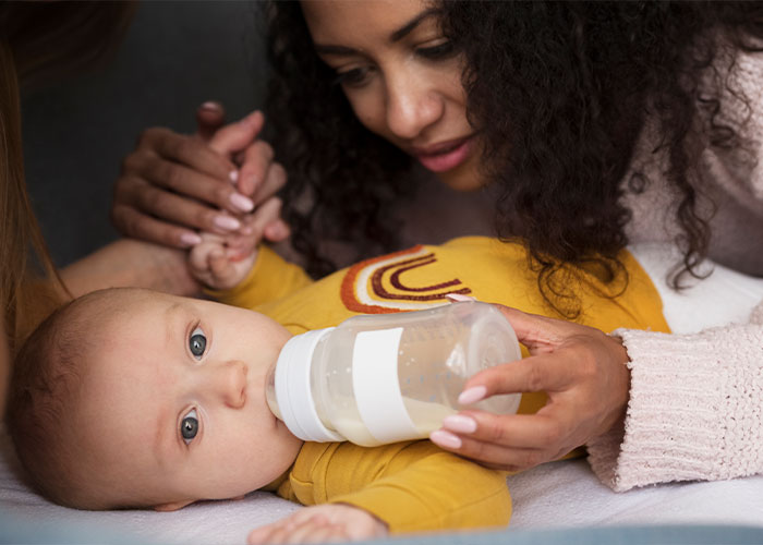 Woman feeding baby with a bottle, highlighting nurturing aspects of parenting.