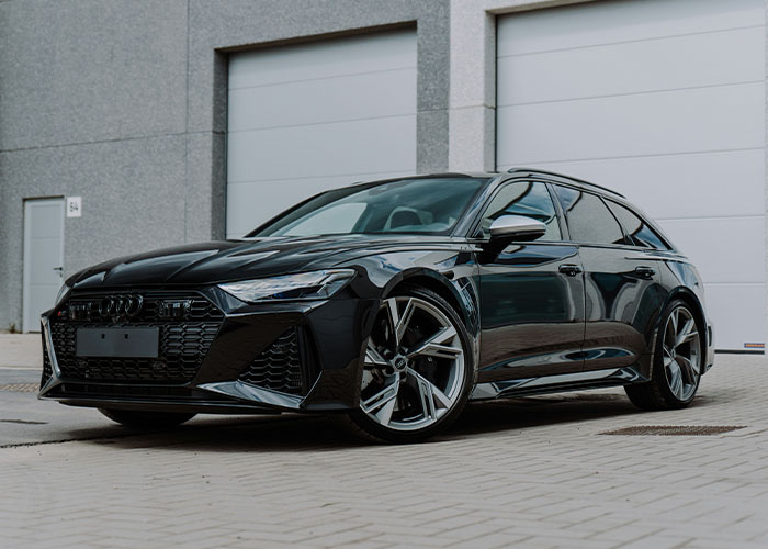 Sleek black Audi car parked in front of industrial garage doors.