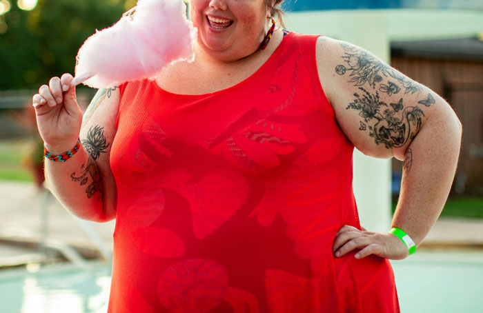 Person in red dress holding cotton candy, smiling outdoors; highlighting overlooked mental health issues.