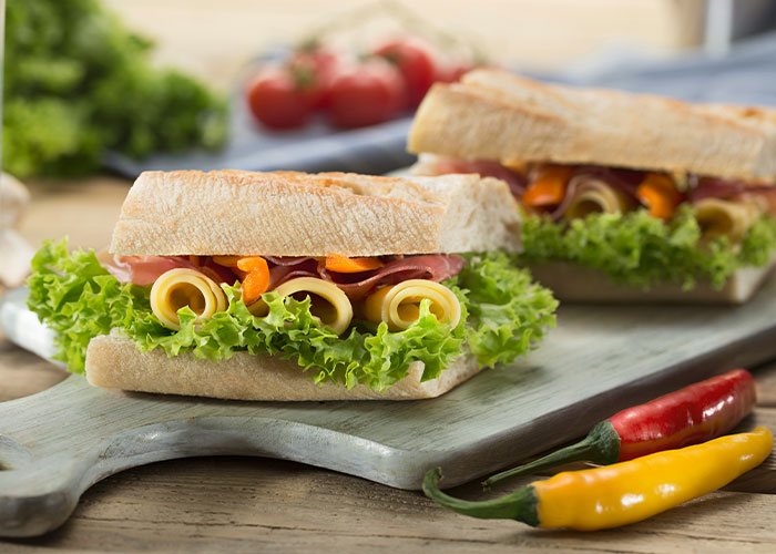 Sandwich with lettuce, cheese, and ham on a cutting board, highlighting unserious reasons for brand boycotts.