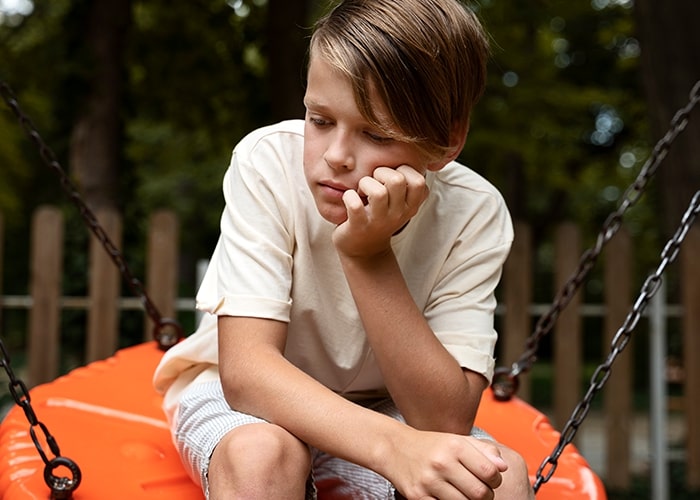 A thoughtful child sitting on a swing, symbolizing common parenting mistakes.