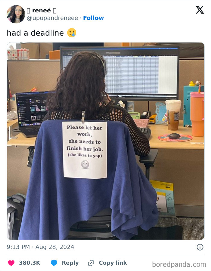 Woman at desk, funny sign on chair about not talking at work, computer screen in the background.