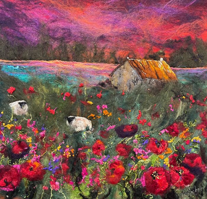Fiber art landscape by Moy Mackay featuring sheep and flowers under a vivid sunset sky.