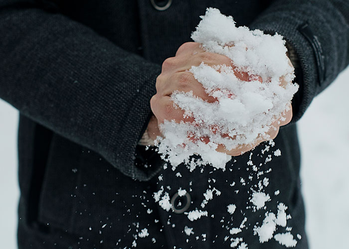 Hands holding snow tightly, capturing one of those memorable dad moments in a snowy setting.