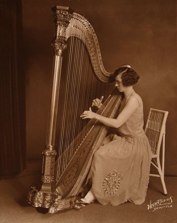 A woman from the past era playing a harp, showcasing rare historical changes over the years.
