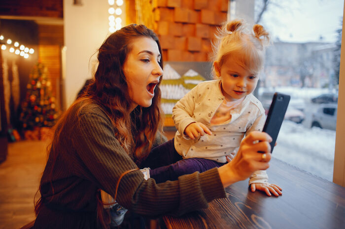 Woman and child with smartphone, demonstrating normal tech interaction.