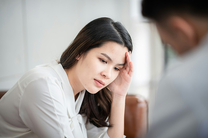 Woman looking concerned, hand on forehead, reflecting on an engagement ring decision.