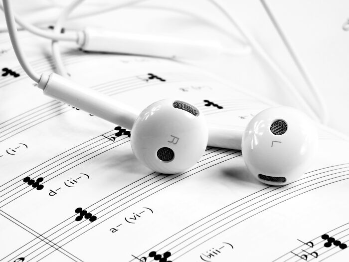 Earbuds resting on sheet music, exploring wild theories in music interpretation.