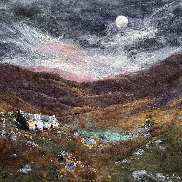 Fiber art landscape with rolling hills, moonlit sky, and a small cottage, showcasing textile scenery techniques.