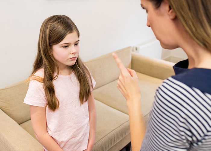 A woman scolding a young girl, highlighting "trashy parent" behavior in a living room setting.