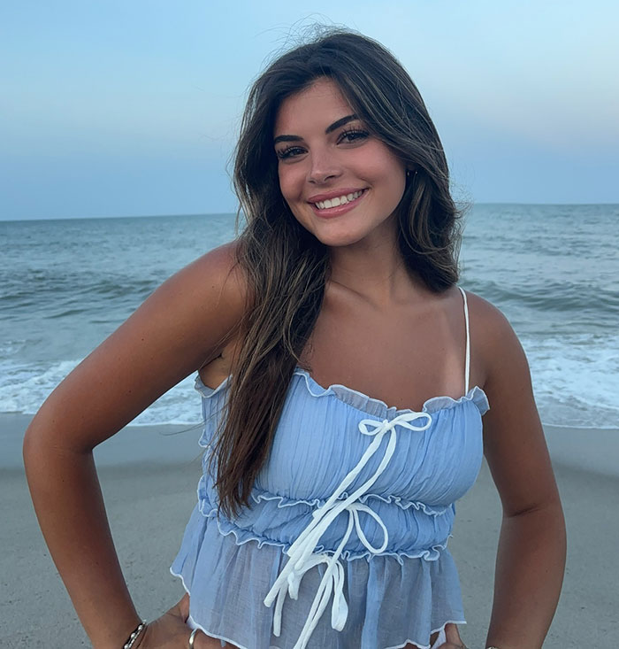 Smiling woman in a blue top at the beach, related to viral romantic note from pilot to plane passenger. Smiling woman in a blue top at the beach, related to viral romantic note from pilot to plane passenger.