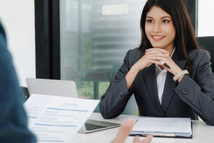 Person in a business suit during a meeting, holding a pen and smiling over documents, discussing mental health issues.