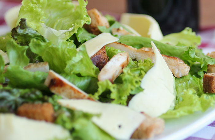 A simple lazy meal salad with fresh lettuce, grilled chicken, croutons, and cheese slices on a white plate.