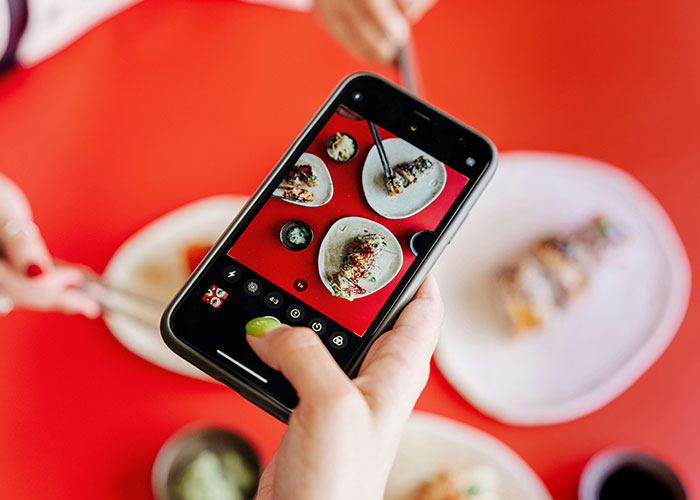 Taking a photo of sushi on a smartphone, capturing life without social media interactions.