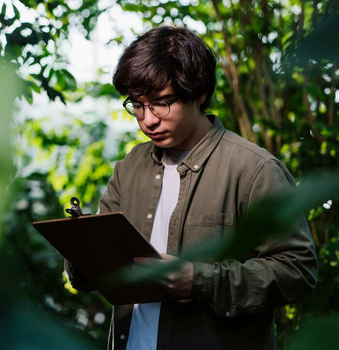 Person analyzing notes on a clipboard in a greenhouse, representing job misconceptions.