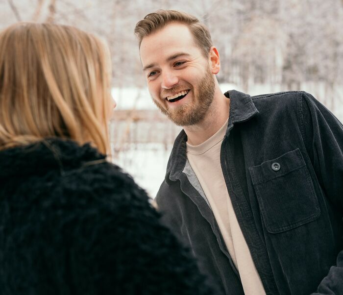 A man and woman smile at each other outdoors, illustrating friendship dynamics.