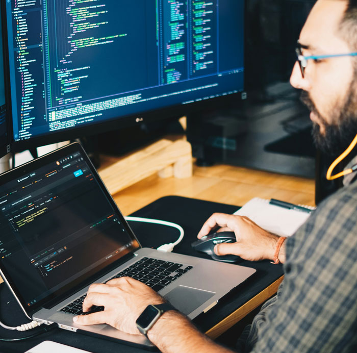 Man working on code at a desk with large monitor, reflecting on work-stealing coworker.