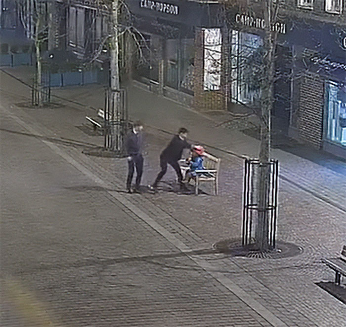 Military personnel interacting with Paddington Bear statue on a city street at night.