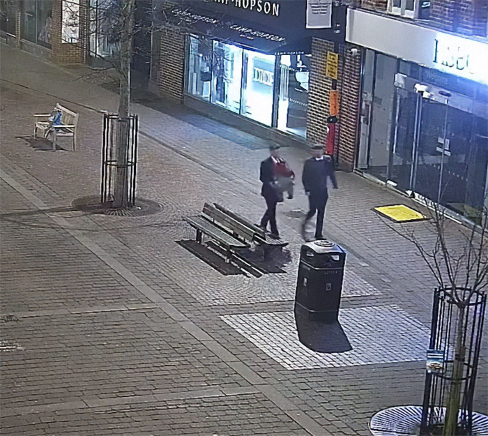 Military personnel carrying Paddington Bear statue on a street at night.