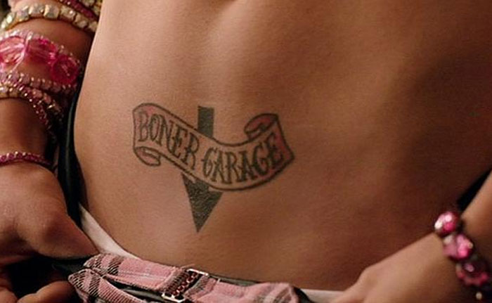 Tattoo on lower back labeled "B***r Garage," surrounded by jewelry, illustrating unattractive body art.